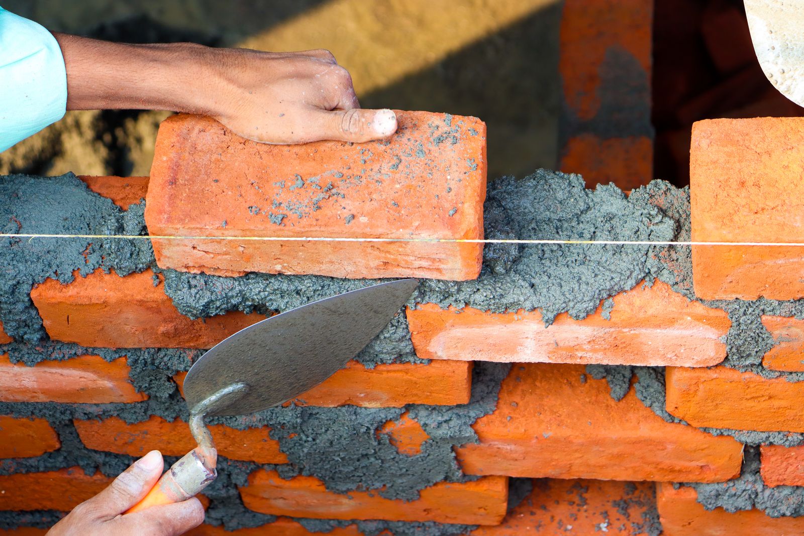 A bricklayer applying mortar with a trowel while laying brick